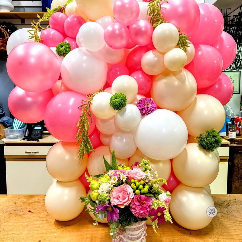 Pink, blush, and cream balloon column accented with fresh florals for a welcome home baby celebration.